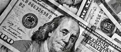 A detailed black and white close-up of overlapping US hundred-dollar bills.