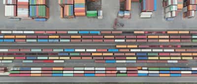 An aerial view of colorful shipping containers arranged in stacks of varying sizes at a storage terminal.