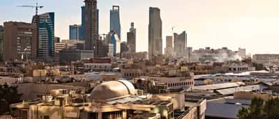 A sprawling view of the Riyadh skyline featuring modern skyscrapers rising above low-lying buildings.