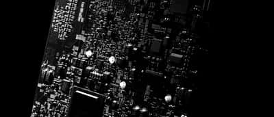 A close-up view of microchips and intricate electronic components on a modern dark circuit board.