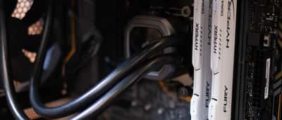 White computer RAM sticks installed alongside a cooling system inside a desktop PC.