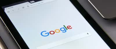 A close-up view of a tablet screen displaying the Google search engine homepage.