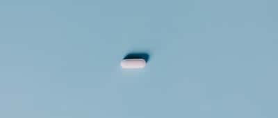 A single white pill centered on a minimalist light blue background.