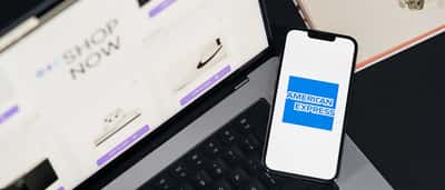 The American Express logo is displayed on a smartphone screen resting on a laptop keyboard.