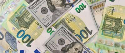 U.S. hundred-dollar bills and hundred-euro banknotes lie overlapping on a flat surface.