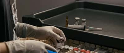 Gloved hands carefully organize medical vials in a sterile laboratory setting.