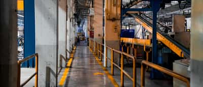 A wide view of a modern industrial factory floor featuring heavy manufacturing machinery and painted yellow safety walkways.
