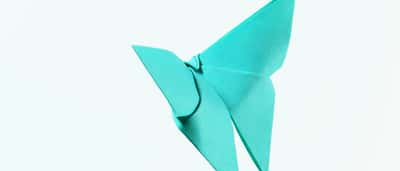 A bright blue origami butterfly folded from paper against a white background.