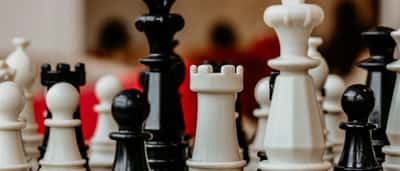 A close-up view of black and white chess pieces clustered together on a chessboard.