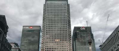 The Citi and HSBC logos top neighboring skyscrapers in London's Canary Wharf under a cloudy sky.