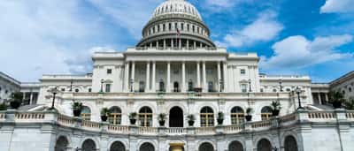 The exterior of the United States Capitol building viewed from the front on a sunny day.