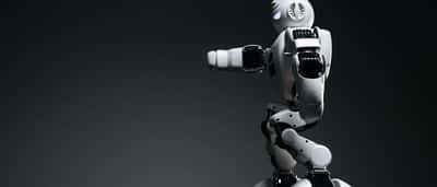 A sleek, white humanoid robot with visible mechanical joints against a dark studio background.