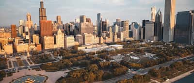An aerial view of the Chicago skyline and Grant Park bathed in warm golden light.