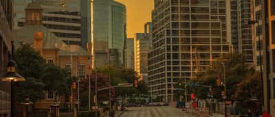 A vibrant golden-hour view of modern skyscrapers illuminating the downtown Dallas skyline.