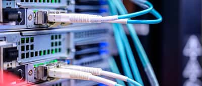 Blue Ethernet cables are connected to the ports of a modern data center server rack.