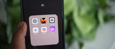 A hand holds a smartphone displaying a folder of artificial intelligence apps, including Anthropic's Claude.