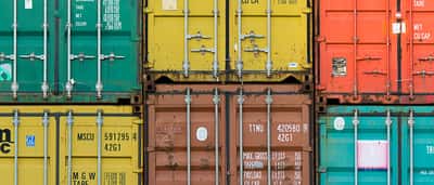 Colorful shipping containers stacked tightly together in a cargo yard.