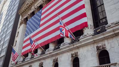An American flag hangs from the ornate stone facade of a historic building.