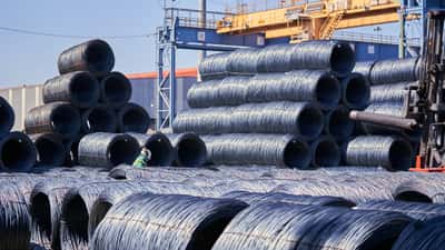 Massive stacks of steel wire coils stored outdoors at a bright industrial site.