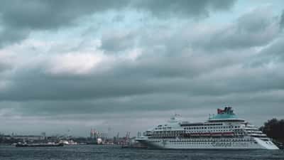 A large cruise ship anchored at port under a heavy, dramatic sky.