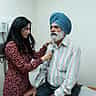 A female doctor uses a stethoscope to examine a senior man in a medical clinic.