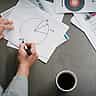 A person's hands drawing and dividing a pie chart with a marker on a piece of paper.