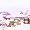 A neat stack of coins resting on printed financial charts and data.