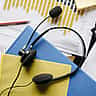 A customer service headset resting on colorful folders and printed financial charts.