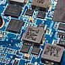 A close-up view of a green electronic circuit board showing intricate metallic pathways and microchips.
