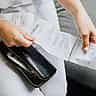 Close-up of a person's hands reviewing multiple store receipts pulled from a black wallet.