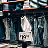 A retail display of denim jeans featuring clear price tags and discount signs.