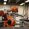 A yellow industrial robotic arm operates within a modern manufacturing or laboratory setting.