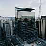 A tall, modern glass skyscraper reflects the dense urban skyline of São Paulo.