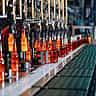Glowing hot glass bottles move along an automated production line in a manufacturing plant.