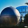 A massive spherical industrial gas storage tank standing against a clear blue sky.