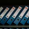 A row of uniform blue document binders arranged neatly on a shelf.