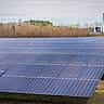 A vast array of blue solar panels stretches across a utility-scale solar farm.