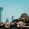 Traditional Chinese architecture in the foreground contrasts with the modern skyscrapers of Beijing's central business district rising against a clear blue sky.