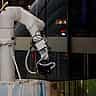 A sleek, modern white robotic arm operates inside a contemporary glass-walled building.