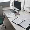 Official business forms and documents arranged neatly on a modern office desk next to a computer monitor.