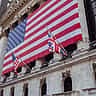 An American flag hangs from the ornate stone facade of a historic building.
