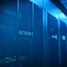 A row of modern server racks illuminated with blue light in a large data center.