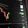 A digital financial screen showing a downward market trend with red candlestick charts.