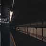 A moody, shadowed view of the Wall Street subway station entrance in New York City.