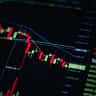 A digital stock market chart displaying a sharp downward trend with red candlesticks on a dark screen.