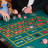 People place stacks of chips on a green casino roulette table.