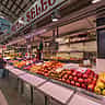 A bustling fruit stall in a Spanish market displaying fresh apples and pears with clear price tags.