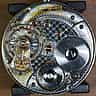 A detailed macro view of an intricate silver and gold watch mechanism with exposed gears and jewels.