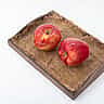 Two identical red apples sit side by side on a wooden tray.