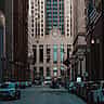 The historic facade of the Chicago Board of Trade building viewed down the center of a busy urban canyon.